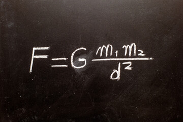 Fórmula de la ley de la gravedad de Isaac Newton escrita a mano en una pizarra con tiza