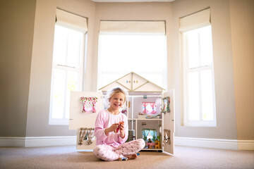 Doll house, portrait and girl child in home playing with toys for growth, development and fun. Smile, sweet and young kid with 3d apartment figure in bedroom for game with happy and positive attitude