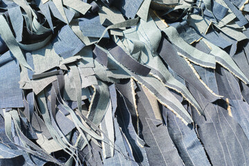 A pile of shredded raw denim fabric in a denim factory. Industrial fabric and fashion manufacture. Stylish blue denim fabric for wholesale and jean recycling.