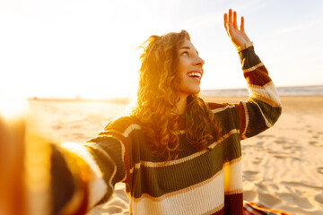 Selfie time. Beautiful curly woman posing by the sea at sunset. Spring time.Travel, weekend, relax...