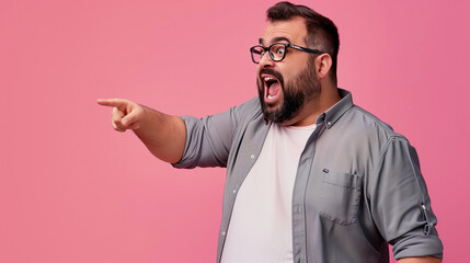 Portrait of excited young fat man wearing glasses and shirt pointing finger at side with open mouth isolated on pink background