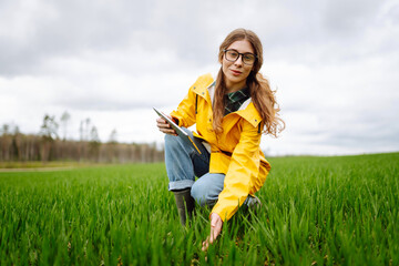 Woman Farmer on a green wheat field with a tablet. Smart farm. The concept of the agricultural...