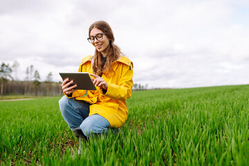 Woman Farmer on a green wheat field with a tablet. Smart farm. The concept of the agricultural...