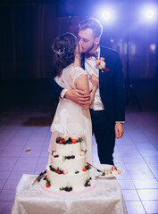 A bride and a groom with their wedding cake