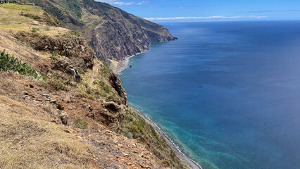 A breathtaking coastal cliff view overlooking the deep blue ocean, with rugged terrain and clear skies.
