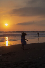 Fototapeta premium Young girl dancing in the sand silhouette during sunset in Lima Peru