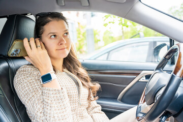 Young woman listening to voice message from mobile phone inside the car
