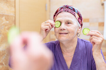 Mature woman taking care of her face. Senior woman standing at the mirror in the bathroom and...