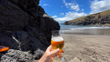 Sandy beach with a glass of beer in hand