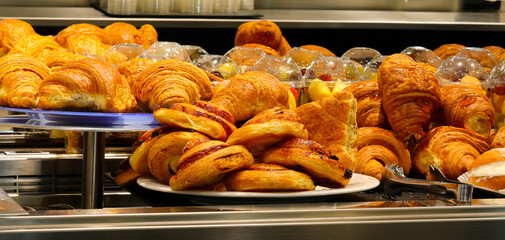 brioches and croissants filled for sale at the bar counter for a sweet breakfast at the start of...