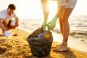 Trash on the beach. Scavengery. A volunteers collects plastic bottles on the ocean shore. The...