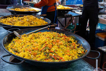 Street food in London, food court on Portobello road Saturday market, fresh prepared colorful paella with rice and sea food big pan, ready to eat