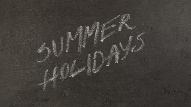 Summer Holidays. Hand writing with chalk on chalkboard. 4K Stop motion animation.