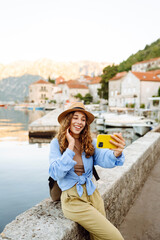 Young woman walks the streets and takes selfie using smartphone camera. Concept of positive...