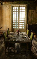 aged dining room with an old table and chairs in front of a window