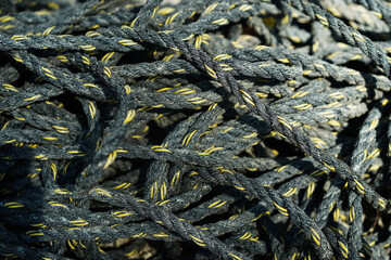 Pile of old black and yellow frayed boat rope background, pattern of twisted ropes, sailing equipment, nautical background. Close up.
