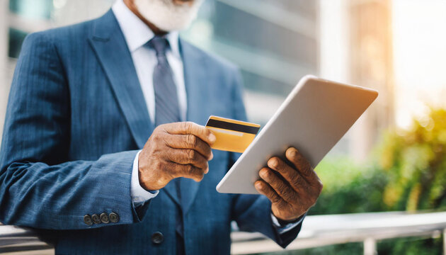 Elderly businessman's hand holding digital tablet and credit card, symbolizing modern senior entrepreneurship