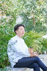 Fototapeta premium コーヒーを飲みながらスマートフォンを操作する男性