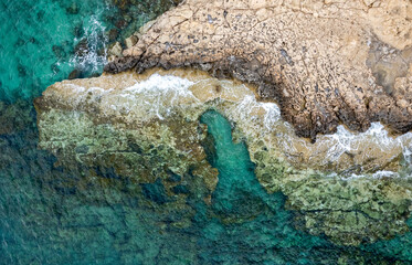 Drone aerial of rocky sea coastline transparent turquoise water. Seascape top view.