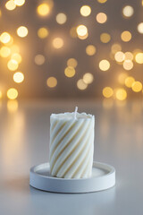 Candle on table with lights in background. Cozy home interior decor. Copy space
