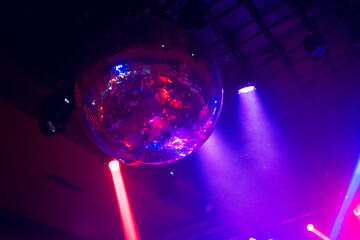 Red and blue colored lights move to the rhythm of the music on the ceiling of a nightclub or...