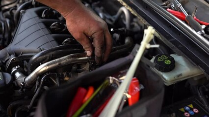 A male auto mechanic is repairing a car. Close-up.