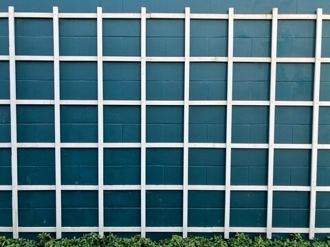 Garden trellis panel isolated on blue stonewall wall texture background
