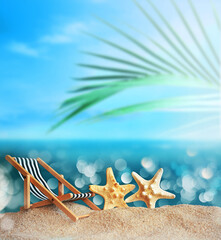 Deckchair, starfish and palm on the sandy beach. Summer time.