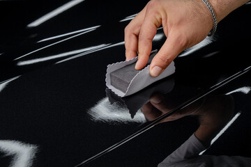 An auto service worker applying a nanocoating to a car part. Ceramic coating of a car.