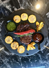 A delicious dish featuring a succulent steak and juicy corn on the cob served on a plate. This classic cuisine pairs perfectly with a squeeze of lemon