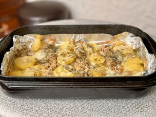 Baked salmon fish steaks with potatoes under mayonnaise lie on baking paper on a black baking sheet. Delicious fast food baked in the oven