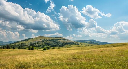 Fototapeta premium Landscape: Serene Mountain View & Rolling Green Hills with Azure Sky & Fluffy Clouds