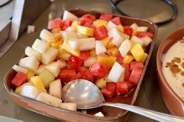 A bowl of fresh cucumber slices a versatile and healthy ingredient A fruit plate consisting of juicy red watermelon, melon, pineapple, all diced and lying in a beautiful bowl for buffet meals in a
