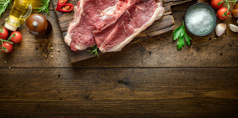 Two raw beef steak on wooden board on wood table with copy space top view
