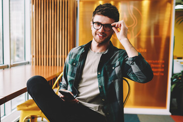 Portrait of handsome smiling smart professional designer wearing spectacles looking at camera while...