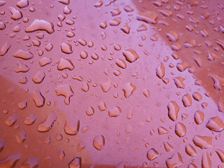 Close-up of the red surface of car paint with raindrops