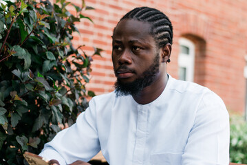 Cheerful male tourist portrait dress in white wear dashiki ethnic smiling at city street or small town background. African American travel model have free time. Millennial generation and gen z people