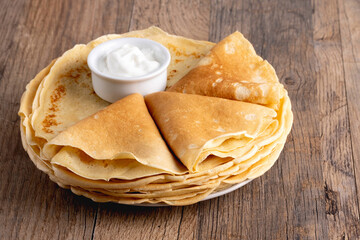 Pancakes with sour cream on a wooden table