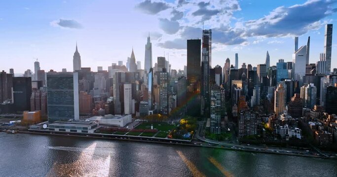 Modern futuristic skyline of New York, the USA. Flight above the East River along the beautiful waterfront with skyscrapers lit with sunlight.