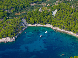 AERIAL: Scenic shot of a rugged shore of Hvar island with a few anchored boats - obrazy, fototapety, plakaty