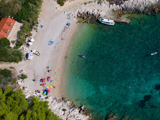 TOP DOWN: Tourists are having fun at scenic pebble beach with turquoise water.