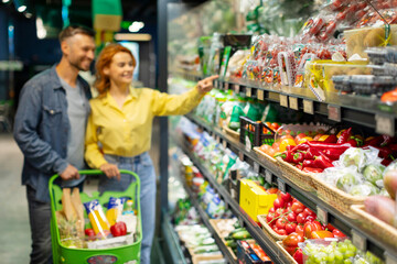 Grocery shopping. Young couple choosing groceries in supermarket, selective focus on fresh...