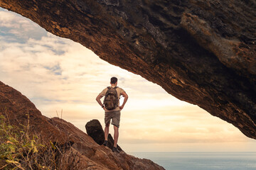 man hiker standing on a mountain looking out at the sea 