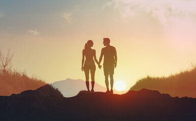 Man and woman walking together holding hands at sunset. People love and relationships.	