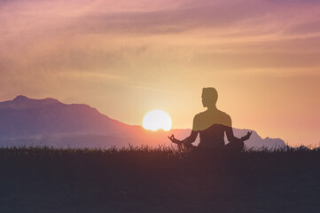 Man in yoga pose, zen meditation at sunset.
