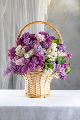 A basket of flowers with purple and white flowers. lilacs in a basket on the table