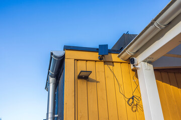 Close-up view of an outdoor security camera and an outdoor lamp with solar panels on the facade of...