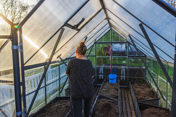 Close-up view of a woman using a steam cleaner to tidy up a greenhouse, preparing it for the new...