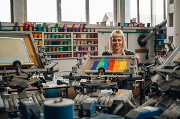 Print shop worker silkscreen printing at facility.