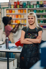 Print shop worker with arms crossed smiling at the camera at facility.